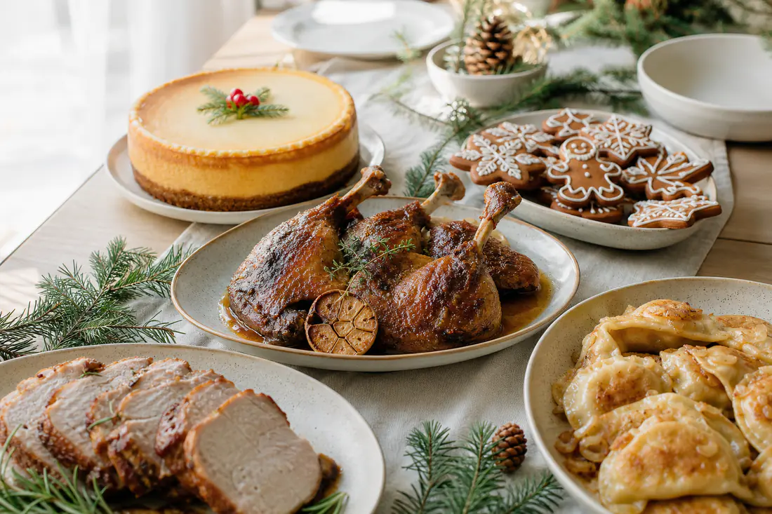 Świąteczny stół z pieczoną kaczką, plastrami pieczeni, rumianymi pierogami i pierniczkami